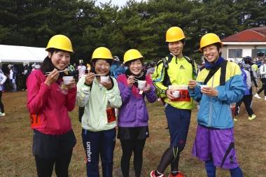 安乗崎エイドで志摩産のふぐ汁を楽しむ参加者。「このイベントではおそろいの黄色いヘルメットをかぶるんです。他の参加者からも声をかけられます！」　