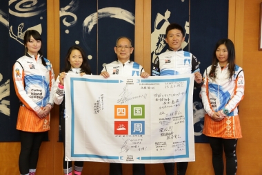 熊谷幸三・徳島県副知事（写真中央）と四国一周サイクリングのフラッグを持って記念撮影。副知事は２日で徳島県内を400kmサイクリングしたこともある健脚の持ち主だ。