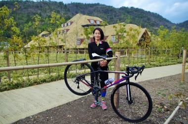 たねやグループ社会部部長の小玉恵さん。八幡山で取れた竹で作ったバイクラックとともに